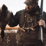 A millenial duck hunter holds a mallard.