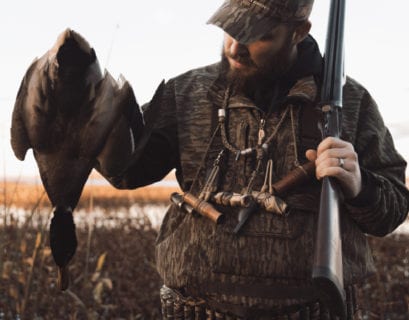 A millenial duck hunter holds a mallard.